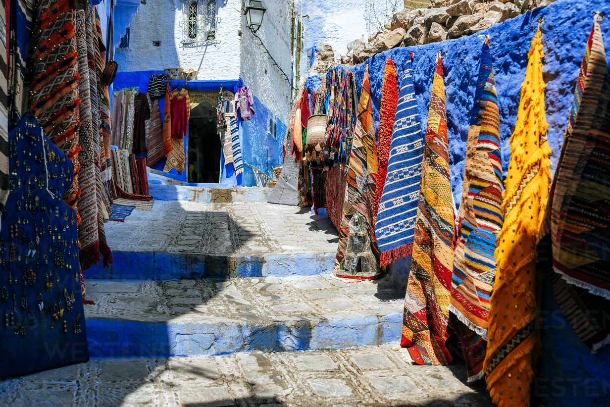 guide to travel in Chefchaouen, Street with shops and carpets collages in Chefchaouen.